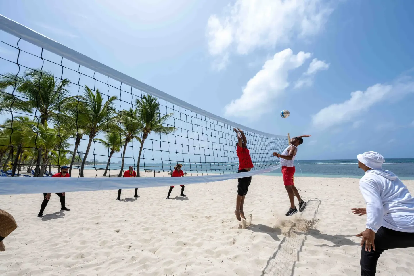 Beach volleyball players jump at the net at Coral Costa Caribe Beach Resort.