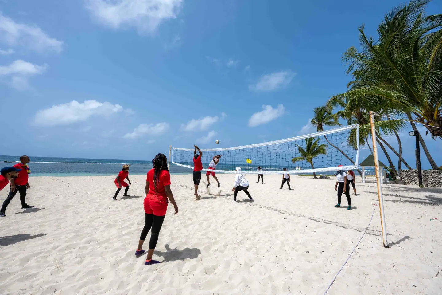 Guests play beach volleyball by the ocean at Coral Costa Caribe Beach Resort.