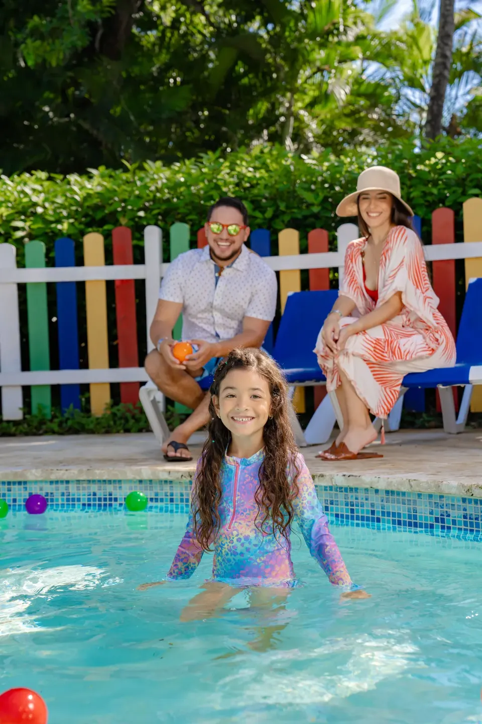 A child stands in a small pool while adults sit nearby at Coral Costa Caribe Beach Resort.