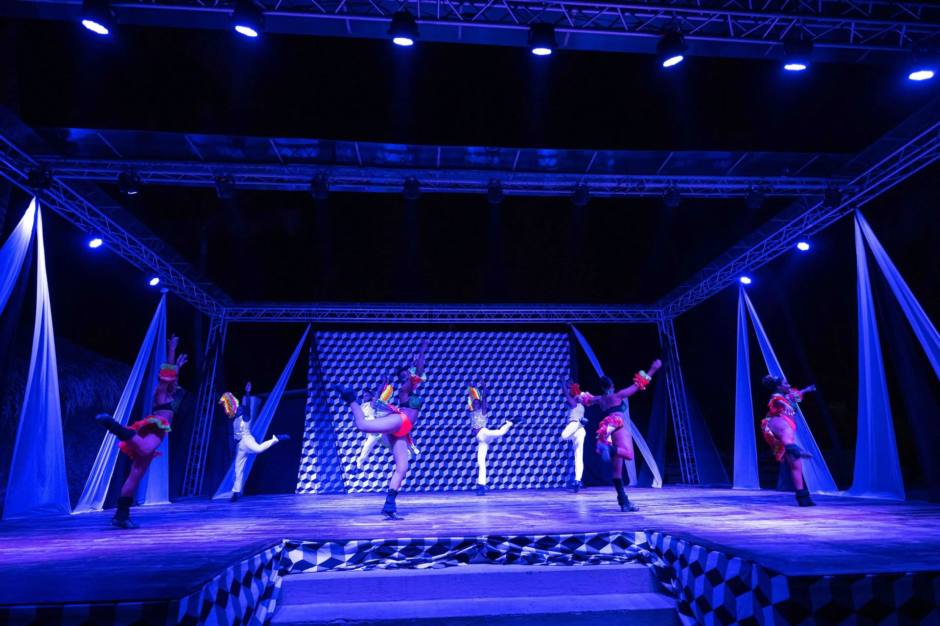 Dancers perform on a blue-lit outdoor stage at Coral Costa Caribe Beach Resort.