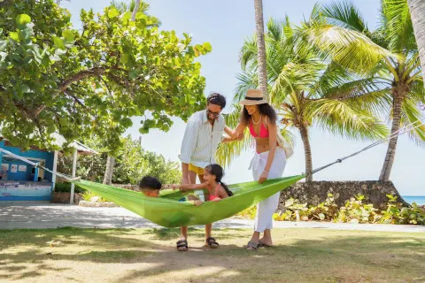 Family gathered around a green hammock at Coral Costa Caribe Beach Resort.
