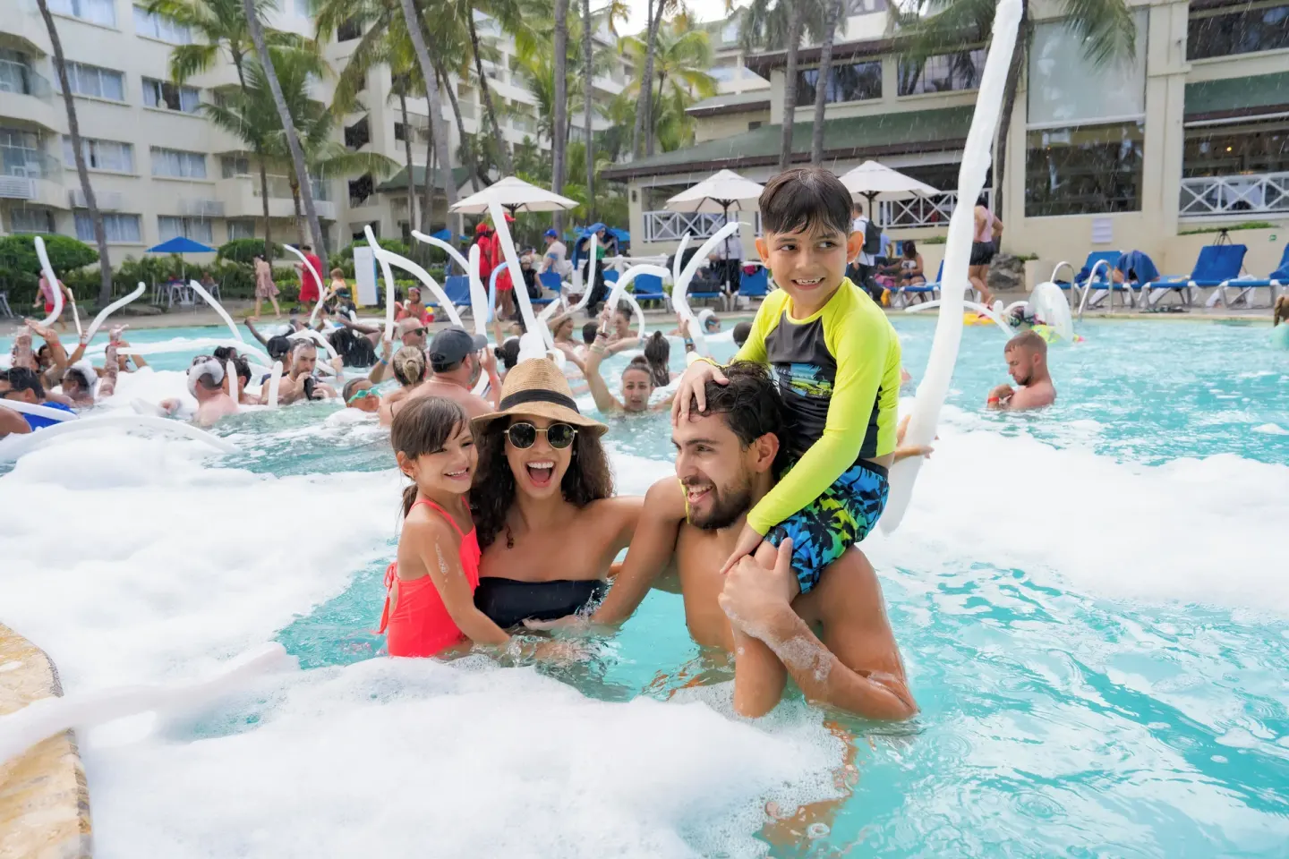 A family smiles in the pool during a foam party at Coral Costa Caribe Beach Resort.