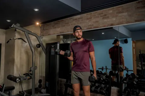 Guest lifting dumbbells beside mirrors in the gym at Coral Costa Caribe Beach Resort.
