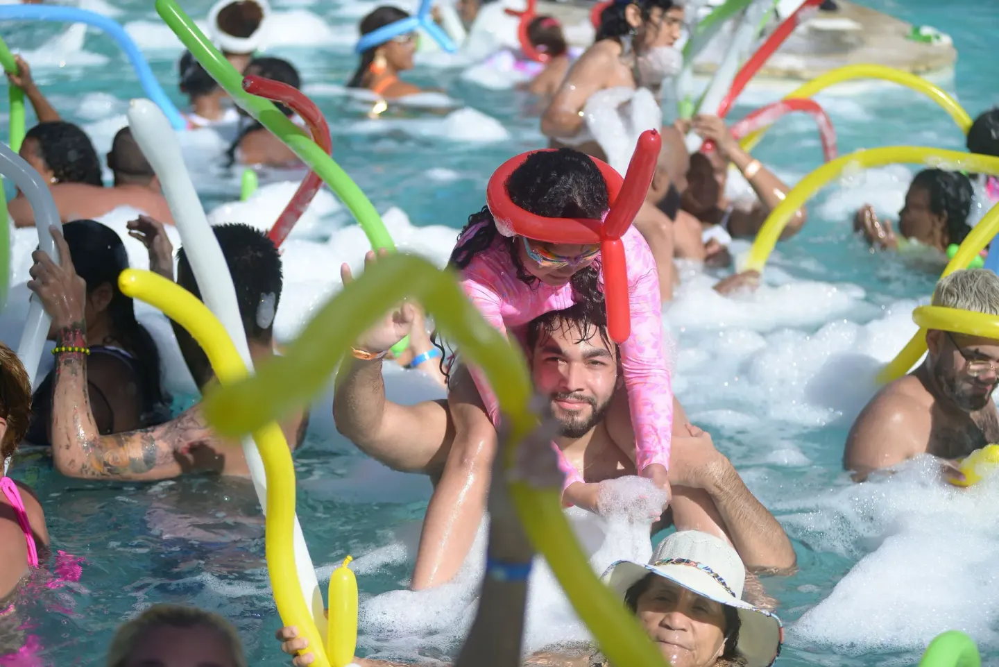 Guests crowd the foamy pool with colorful balloons at Coral Costa Caribe Beach Resort.
