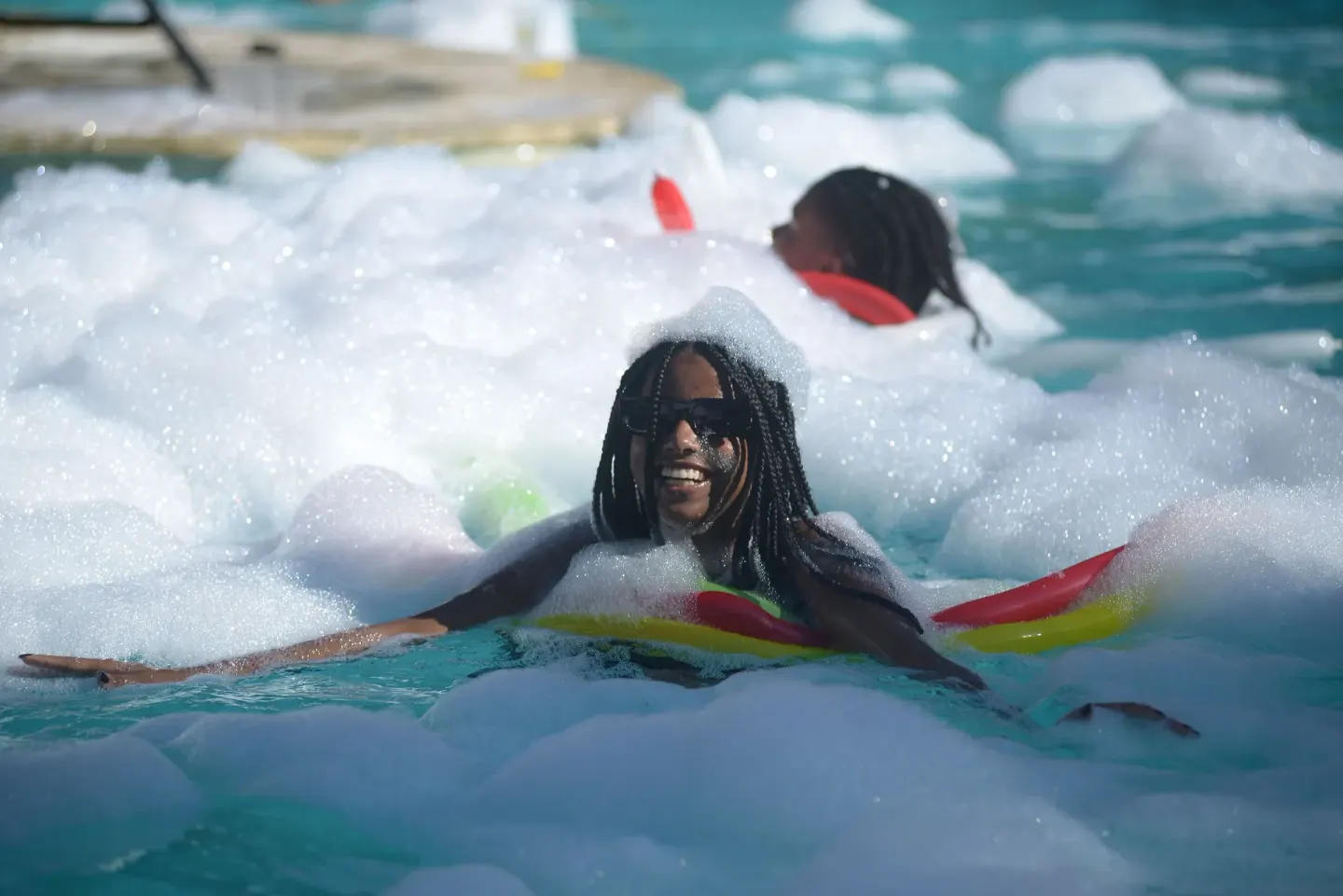 A smiling guest floats through pool foam at Coral Costa Caribe Beach Resort.