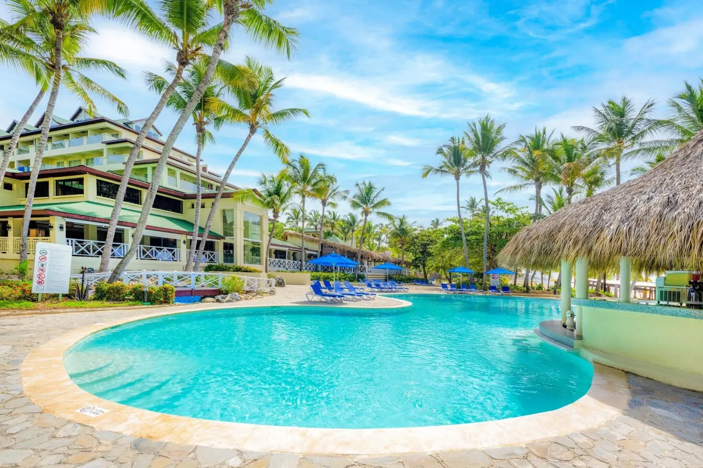 A turquoise pool curves beside palms and resort buildings at Coral Costa Caribe Beach Resort.