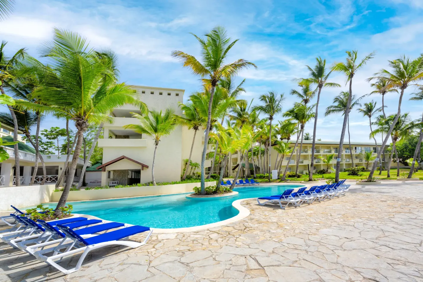 Curving resort pool with blue loungers and palm trees at Coral Costa Caribe Beach Resort.