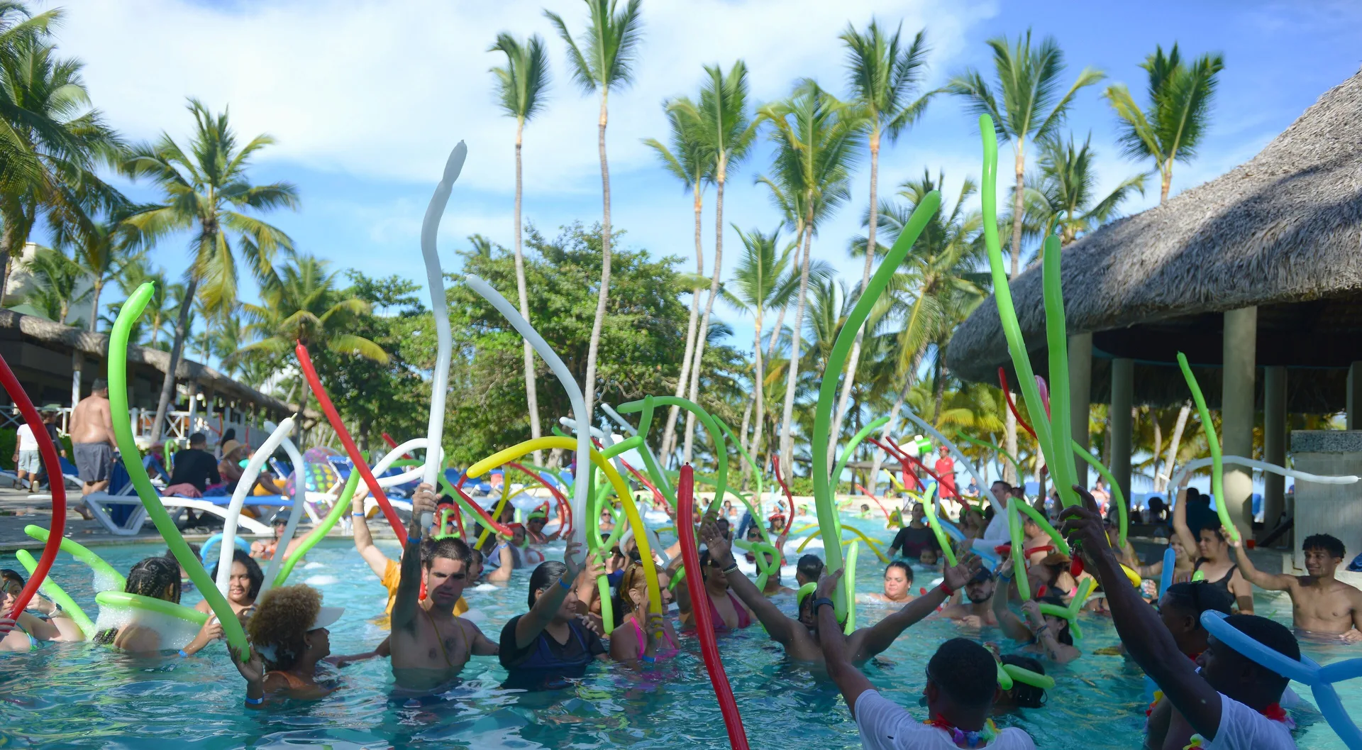 Guests wave pool noodles during a pool party at Coral Costa Caribe Beach Resort.