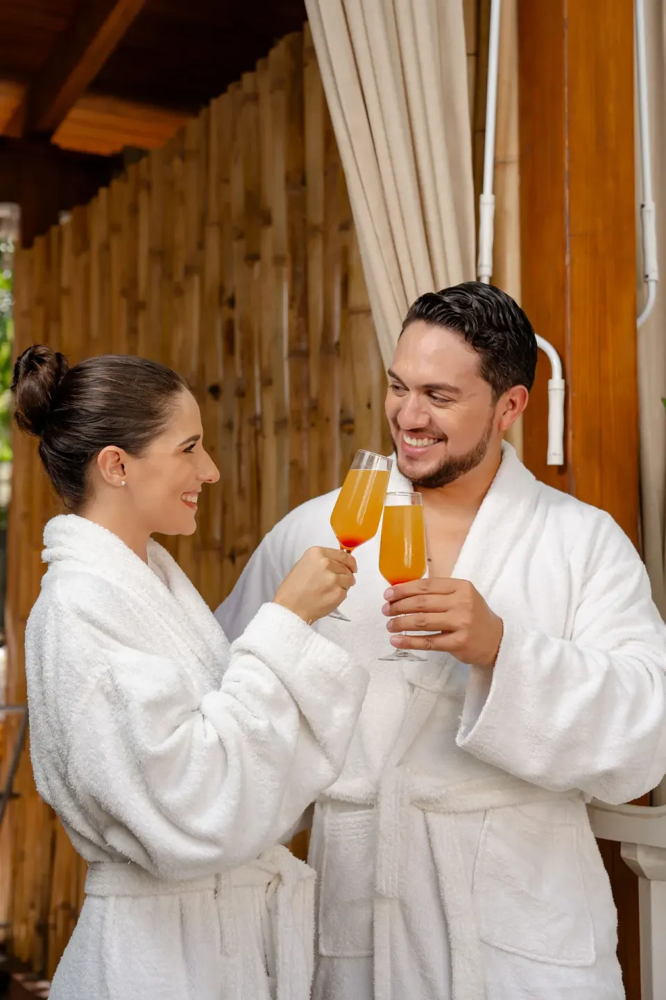 Couple in white robes toasting with drinks at Coral Costa Caribe Beach Resort.