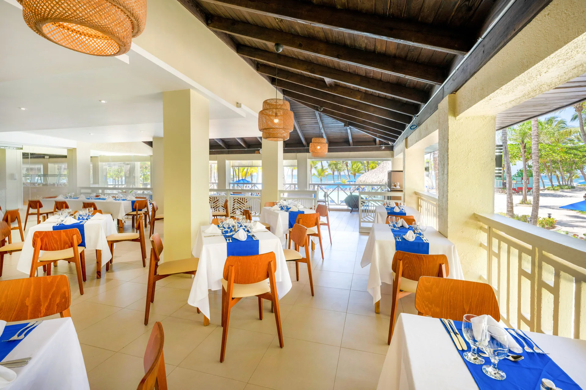 Open-air dining room with blue table runners at Coral Costa Caribe Beach Resort.