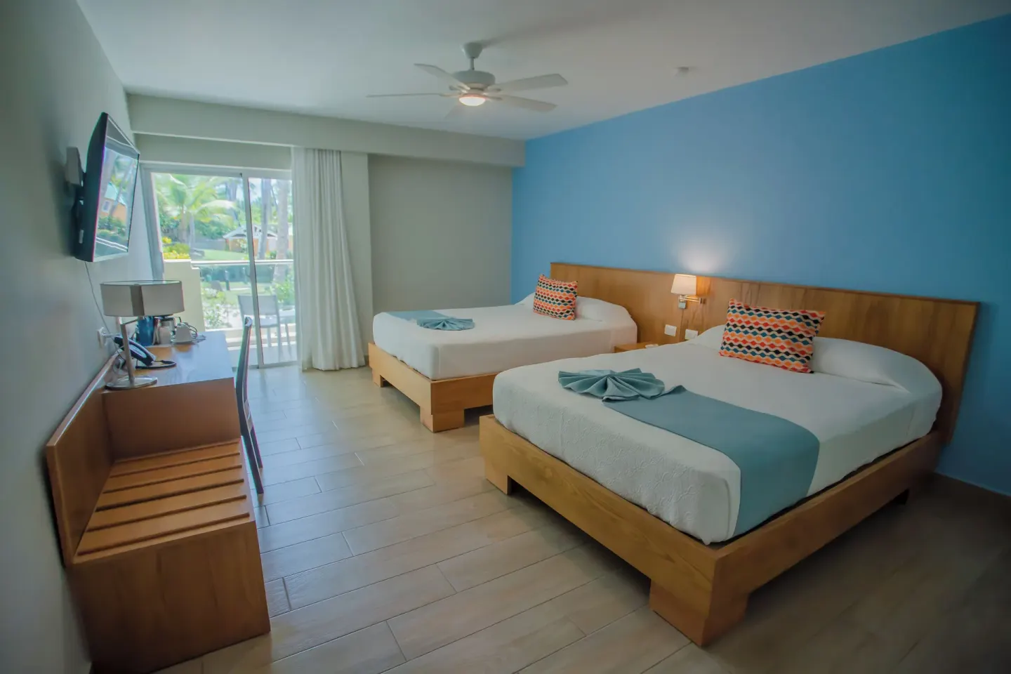Deluxe Room with two beds, balcony, and garden greenery at Coral Costa Caribe Beach Resort.