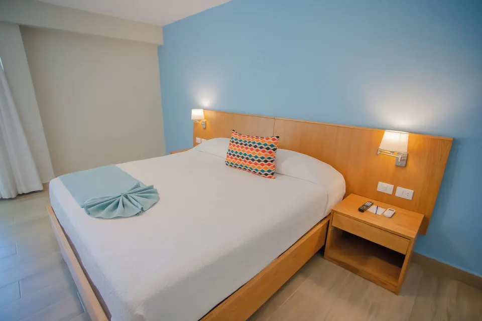 Deluxe ocean view room with king bed and bedside lamps at Coral Costa Caribe Beach Resort.