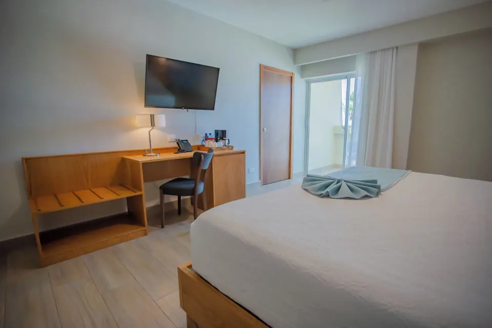 Deluxe ocean view room with king bed, desk, TV, and balcony doors at Coral Costa Caribe Beach Resort.