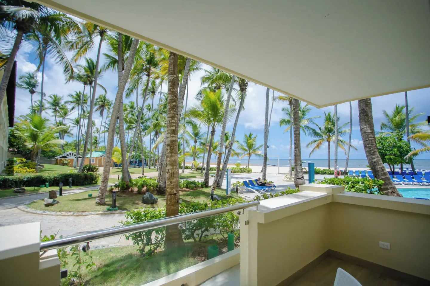 Covered room balcony overlooking palms, pool, beach, and ocean at Coral Costa Caribe Beach Resort.