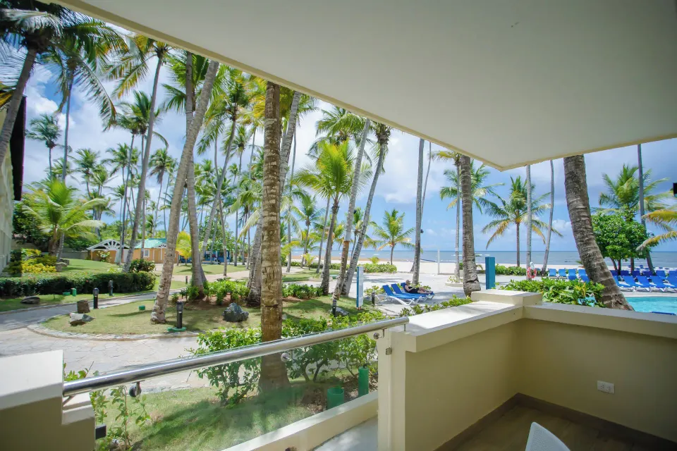Covered room balcony overlooking palms, pool, beach, and ocean at Coral Costa Caribe Beach Resort.