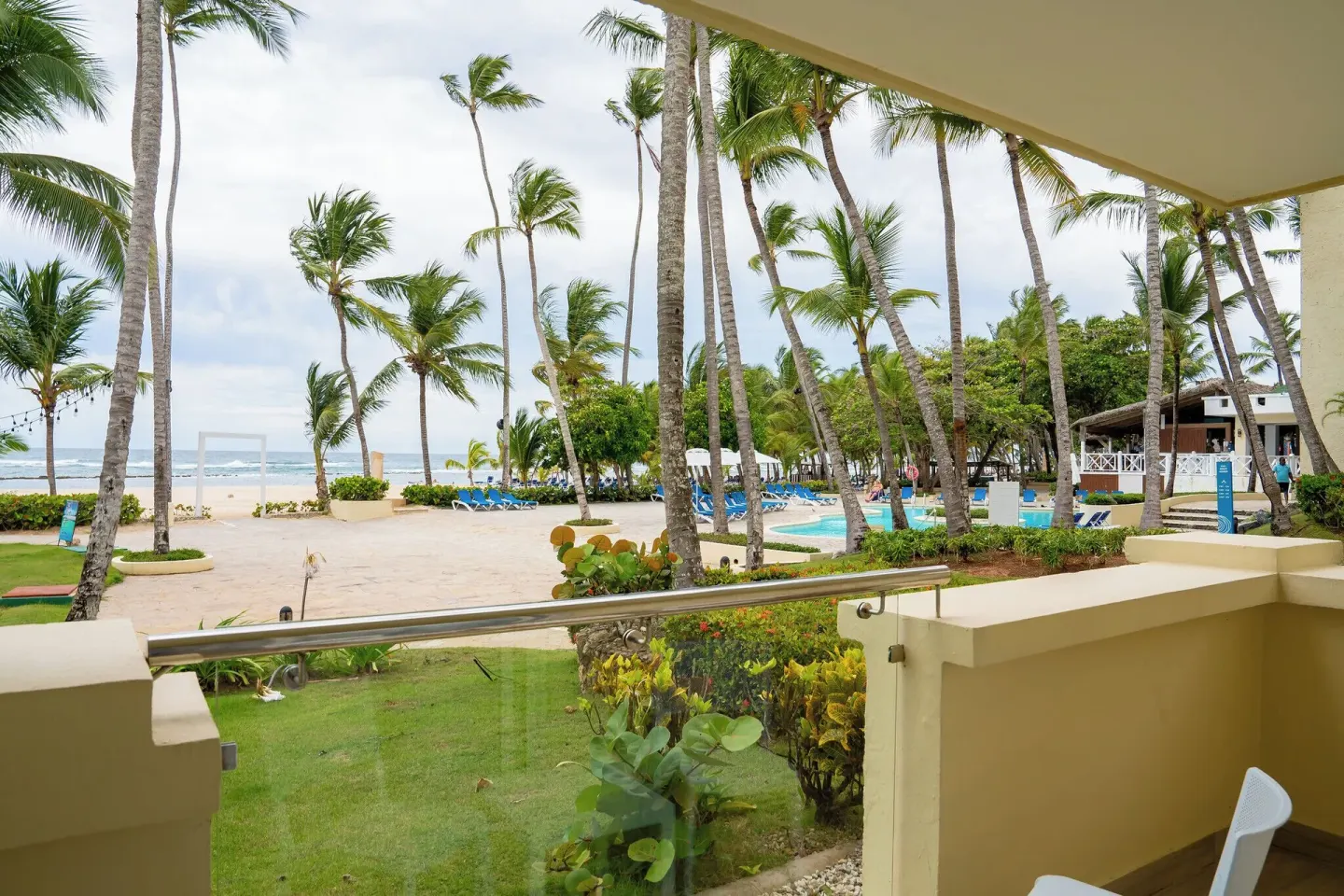 Room balcony view of palms, pool, beach, and ocean at Coral Costa Caribe Beach Resort.