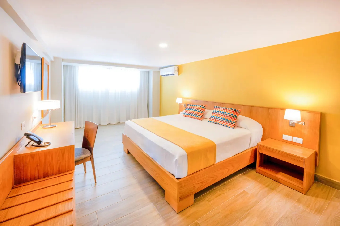 Standard Room Garden View with king bed and bedside lamps at Coral Costa Caribe Beach Resort.