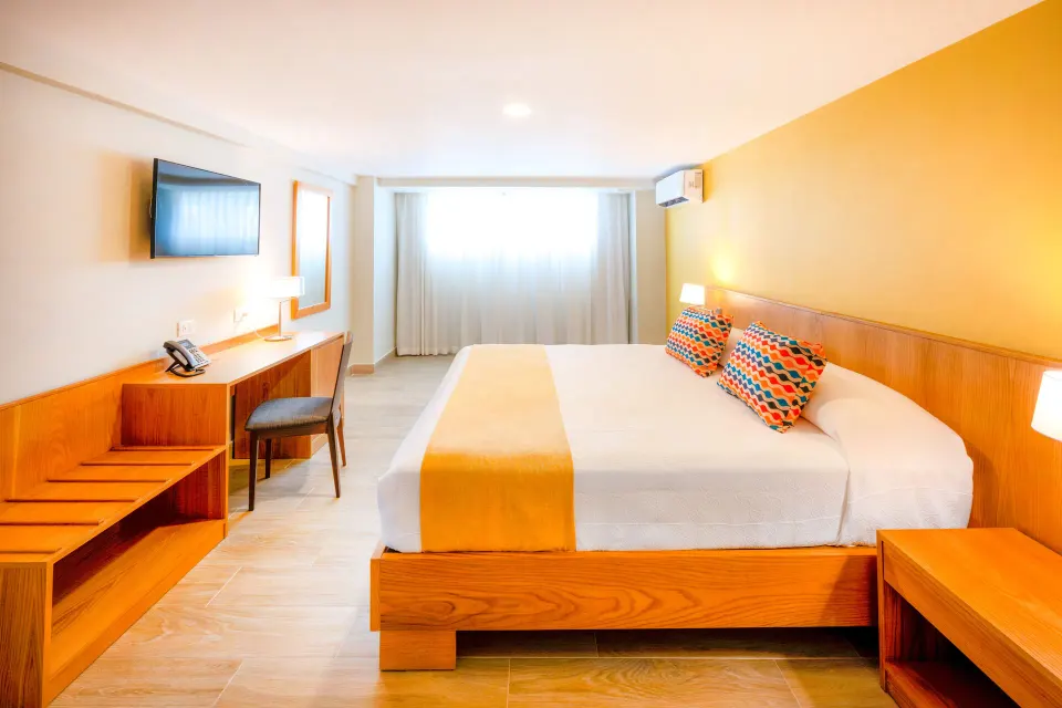 Standard Room Garden View king bed and curtained window at Coral Costa Caribe Beach Resort.