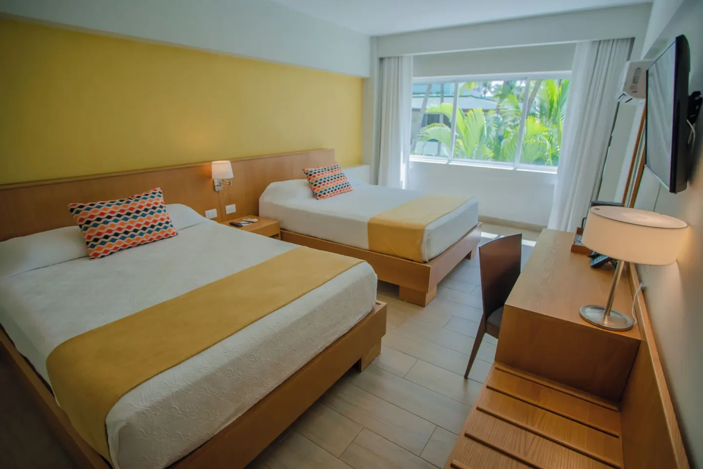 Standard Room Garden View with two beds and garden-facing window at Coral Costa Caribe Beach Resort.
