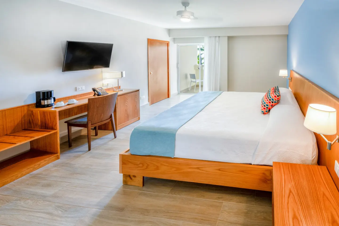 Superior Room with king bed, blue accent wall, and balcony at Coral Costa Caribe Beach Resort.
