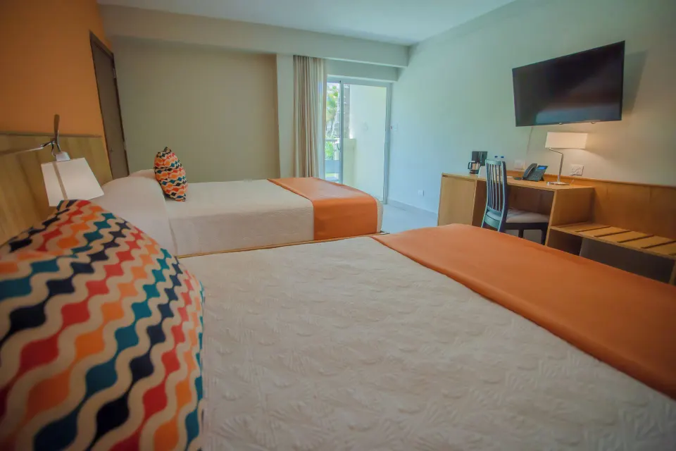 Two-bed Superior Room with desk and balcony door at Coral Costa Caribe Beach Resort.