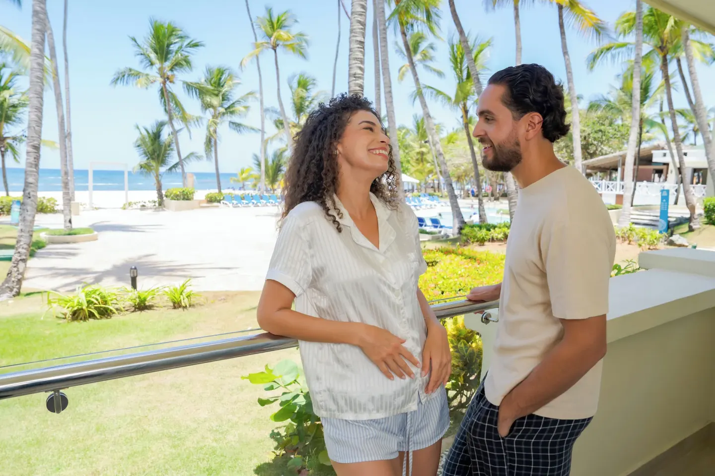 Couple on a Superior Room balcony by the beach at Coral Costa Caribe Beach Resort.