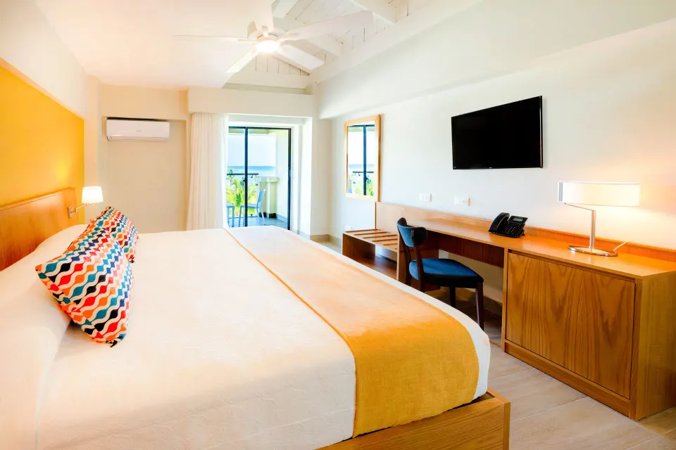 Superior Room king bed with balcony beyond at Coral Costa Caribe Beach Resort.