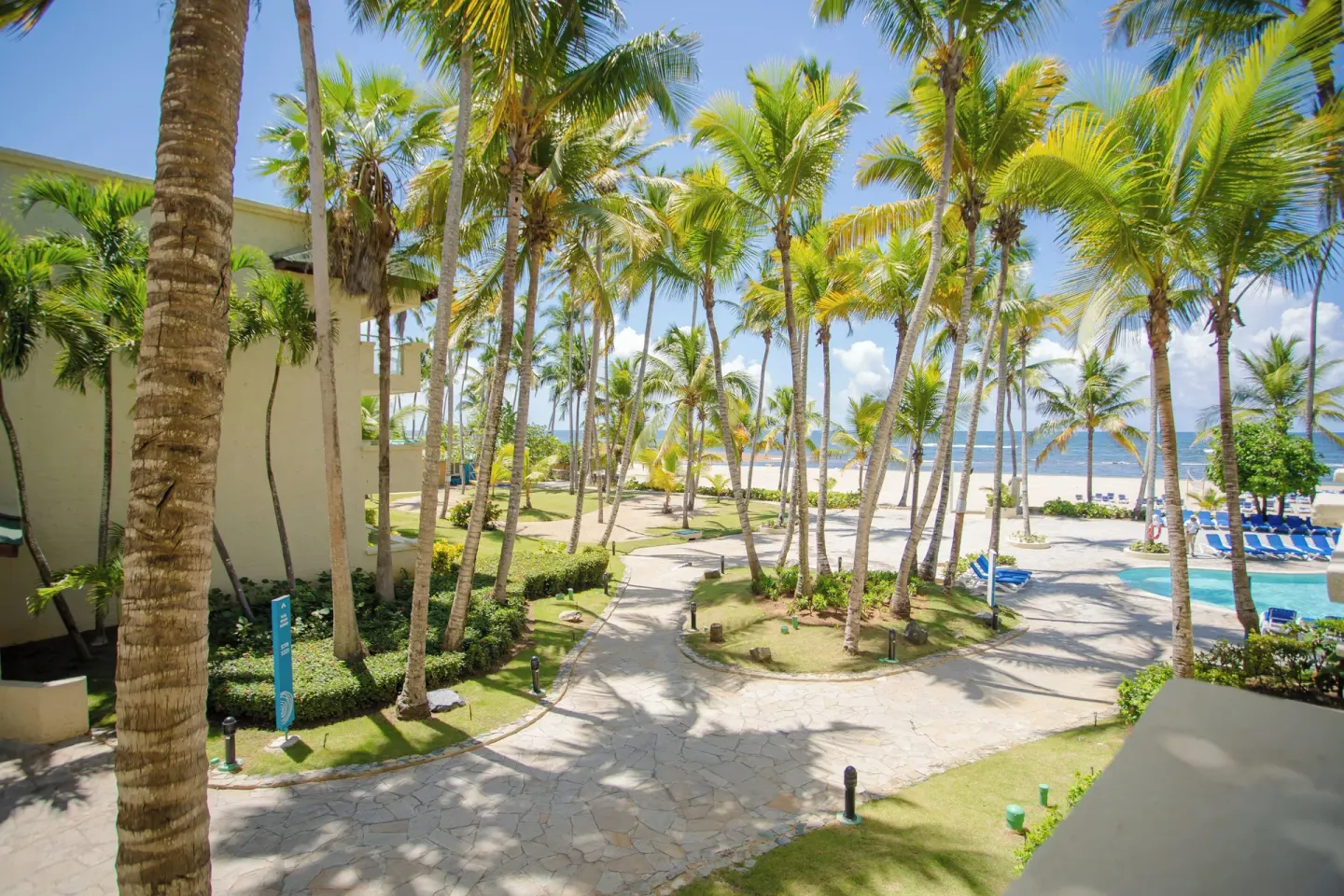Superior Room balcony view of palms, pool, and beach at Coral Costa Caribe Beach Resort.