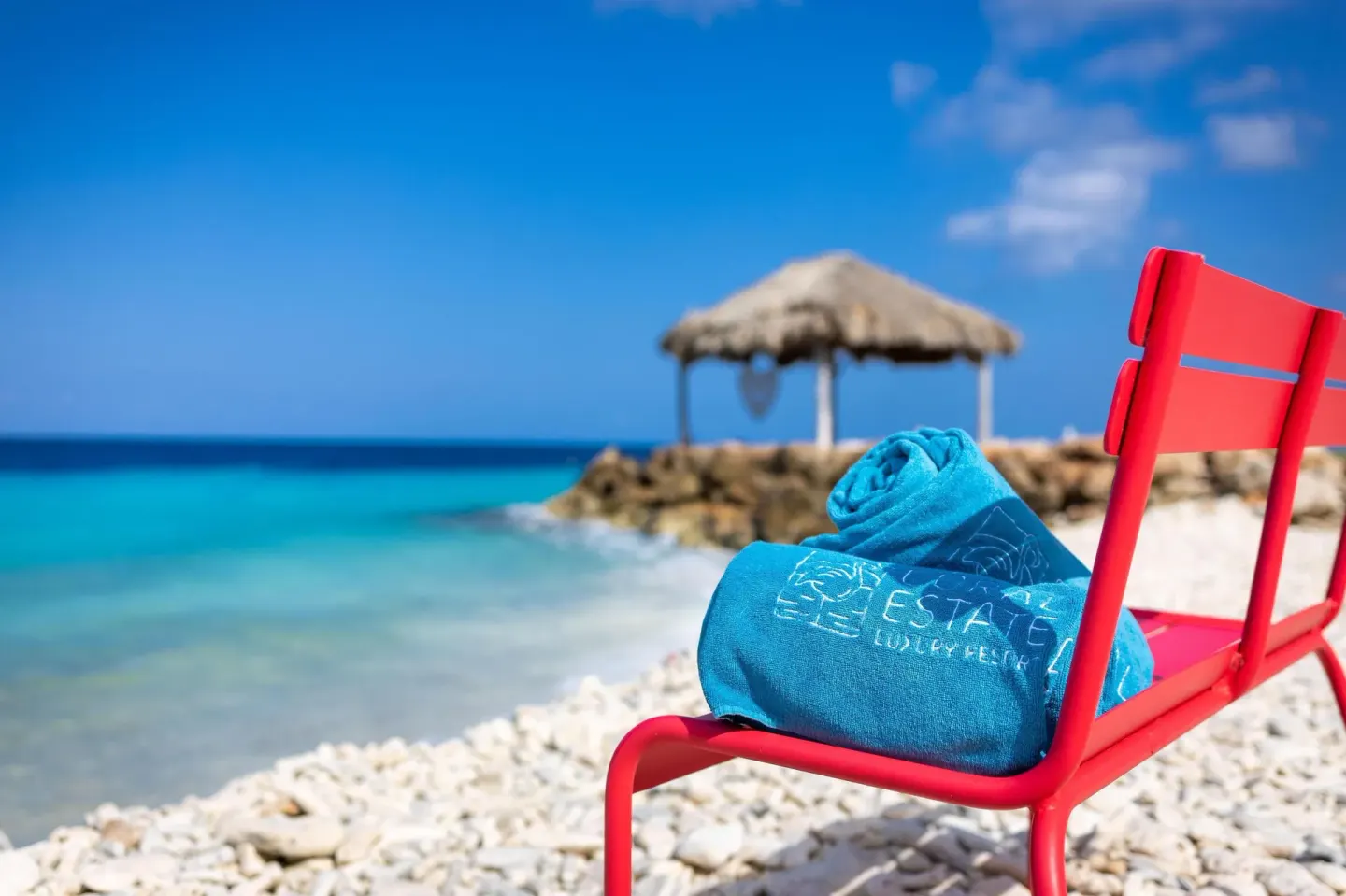 Red beach chair with a blue towel by the water at Coral Estate Luxury Resort.
