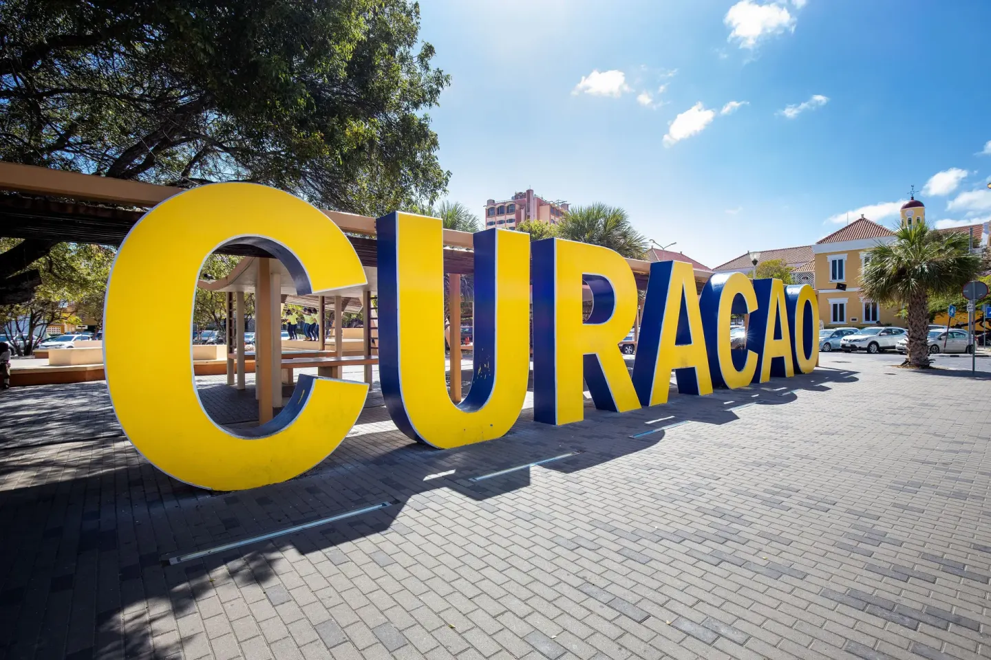 Large yellow Curaçao letters in a sunny town square near Coral Estate Luxury Resort.
