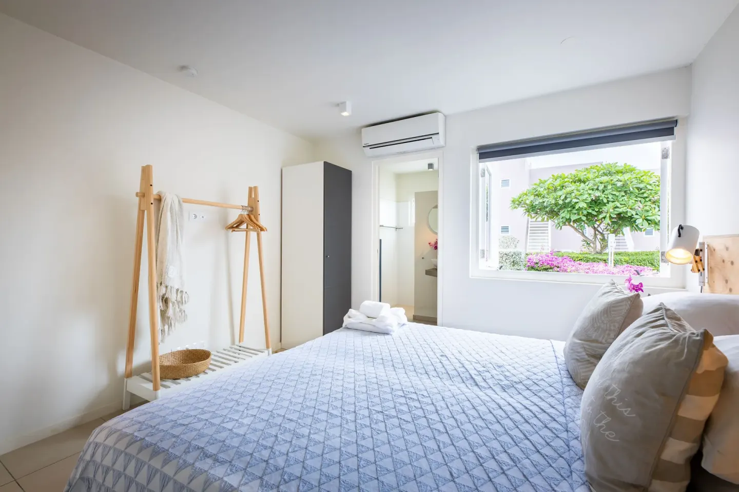 Guest room at Coral Estate Luxury Resort with a bed, open window, wardrobe, and garden view.