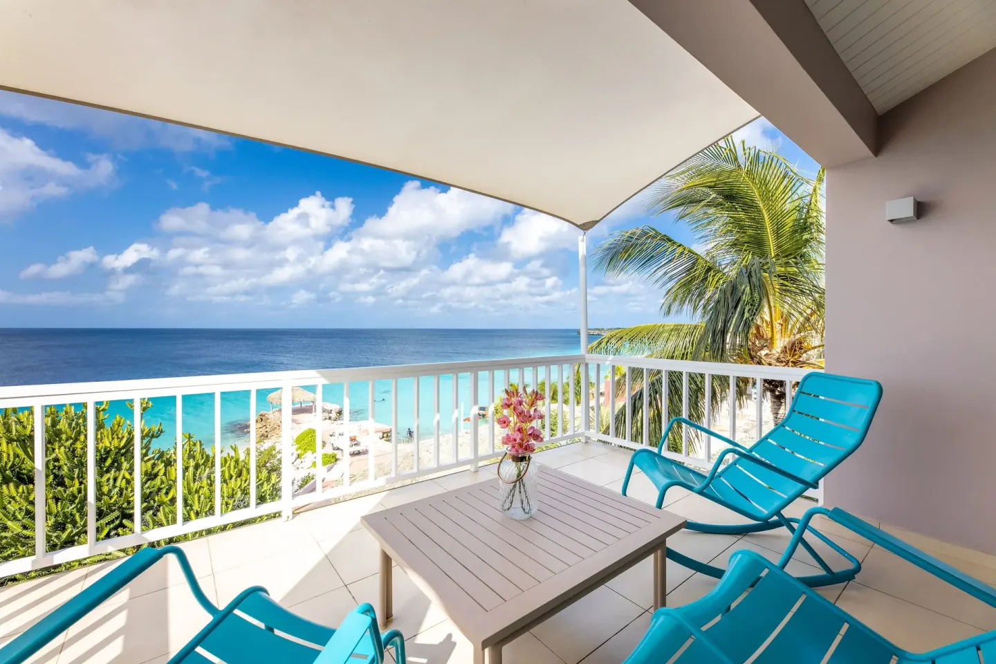 Ocean-view balcony with turquoise lounge chairs at Coral Estate Luxury Resort.