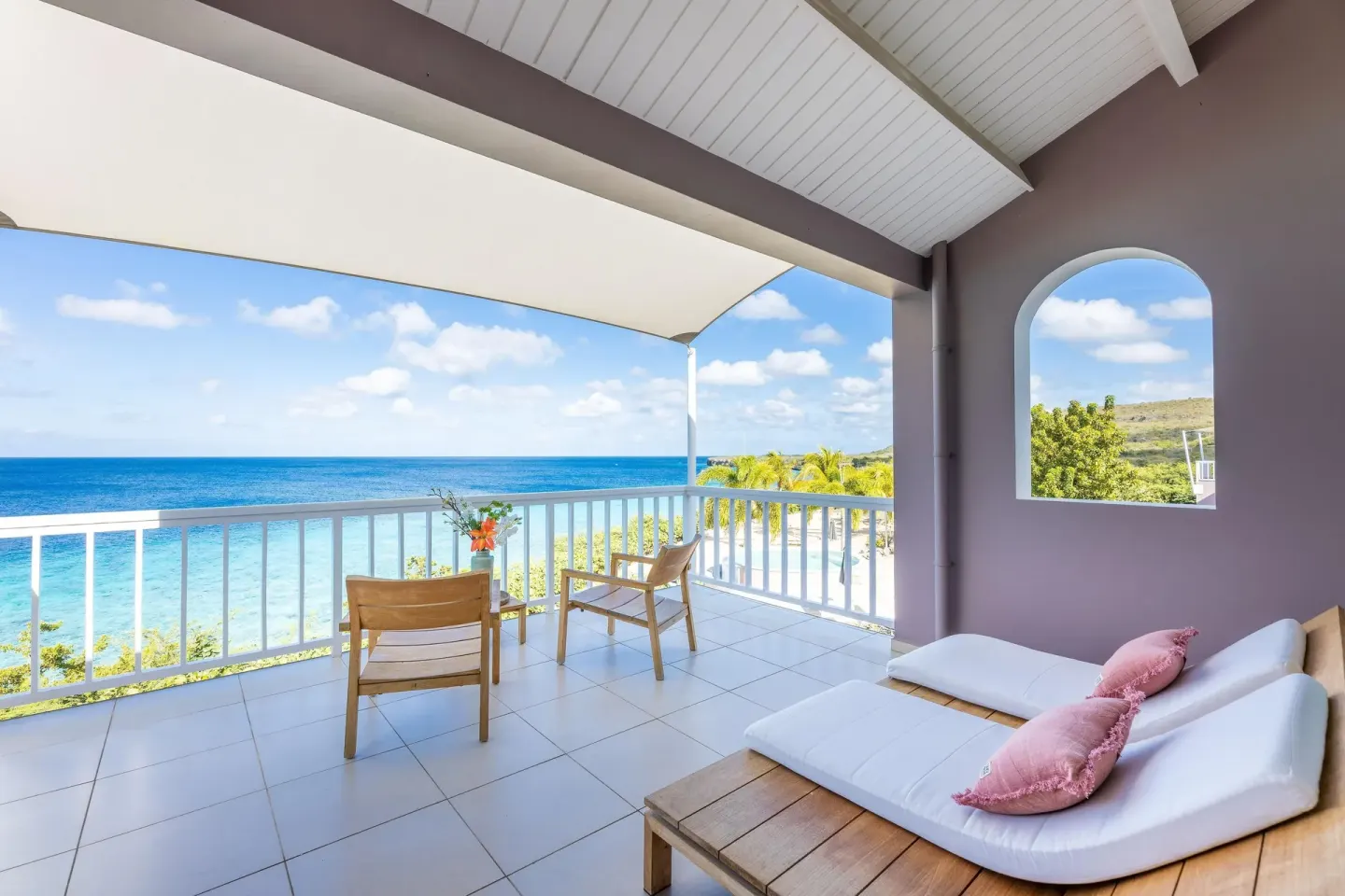 Ocean-view terrace with chairs and a daybed at Coral Estate Luxury Resort.