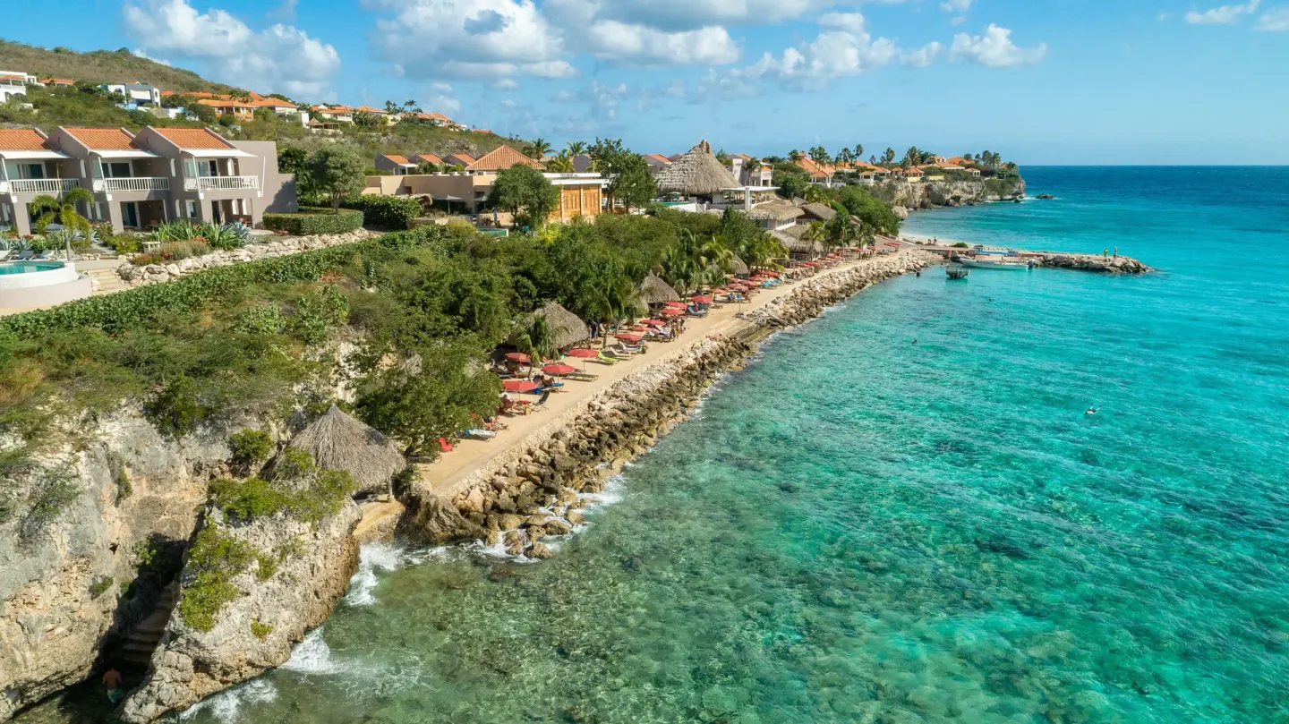 Aerial view of the rocky beachfront and turquoise sea at Coral Estate Luxury Resort.