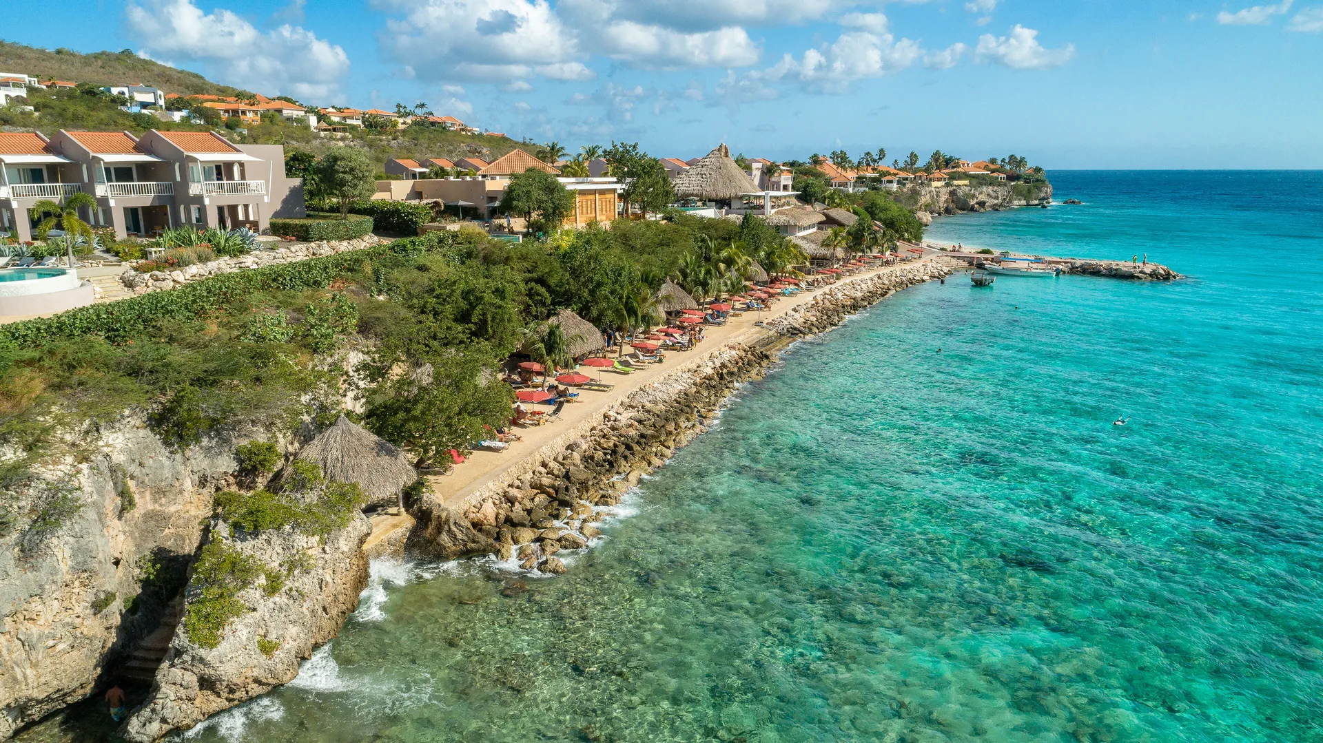 Aerial view of the rocky beachfront and turquoise sea at Coral Estate Luxury Resort.