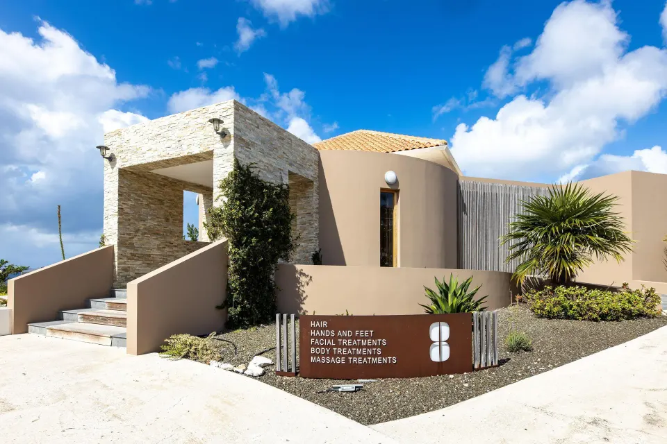 Spa building entrance with treatment sign and desert landscaping at Coral Estate Luxury Resort.