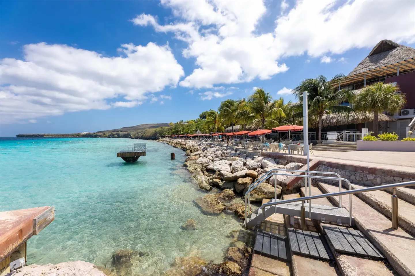 Rocky shoreline and waterfront terraces at Coral Estate Luxury Resort.