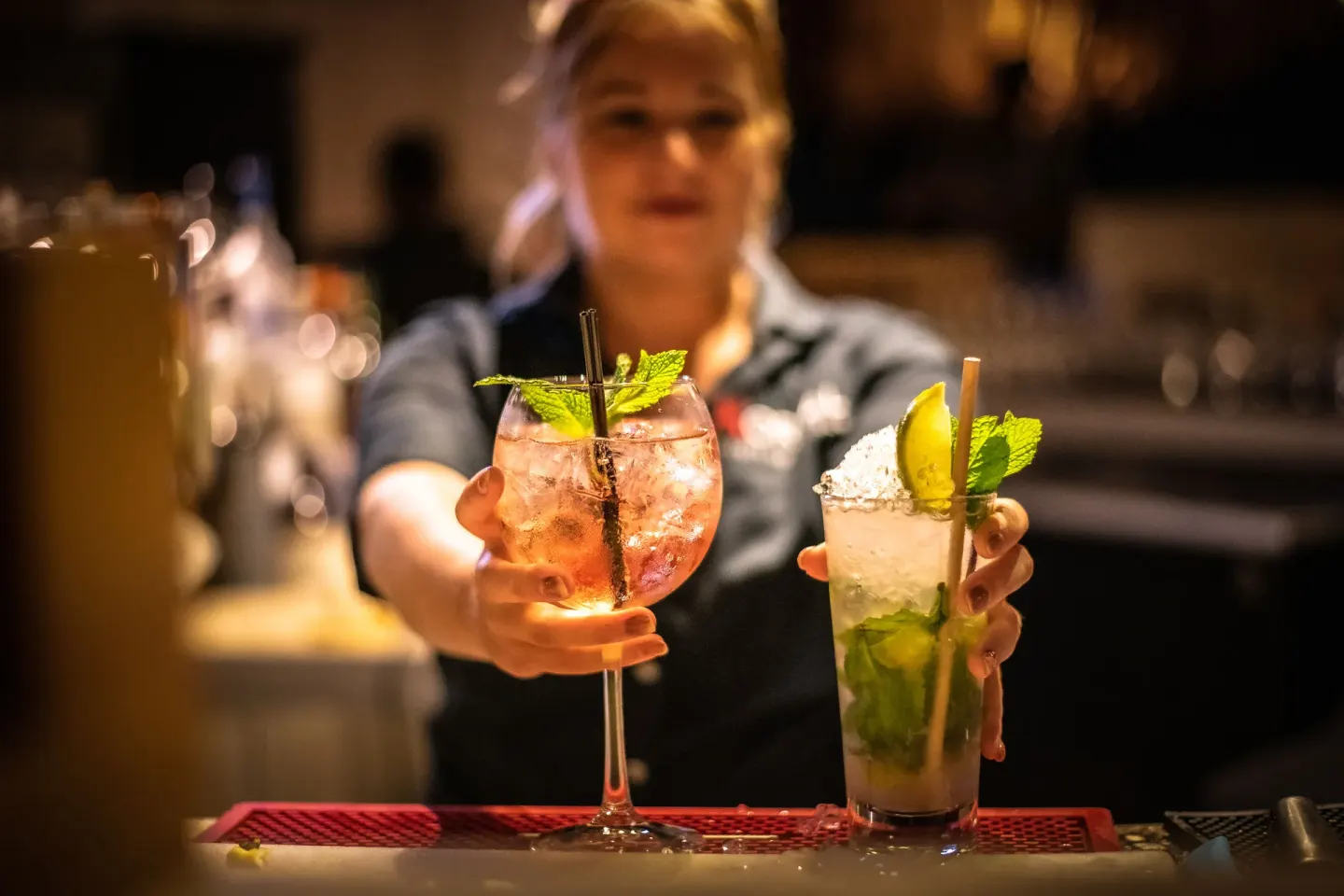 Bartender presenting two garnished cocktails at Coral Estate Luxury Resort.