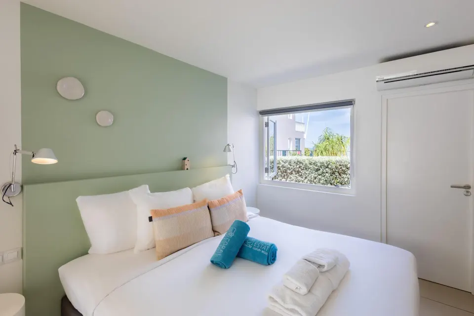 Bedroom with a double bed, green accent wall, and garden window at Coral Estate Luxury Resort.