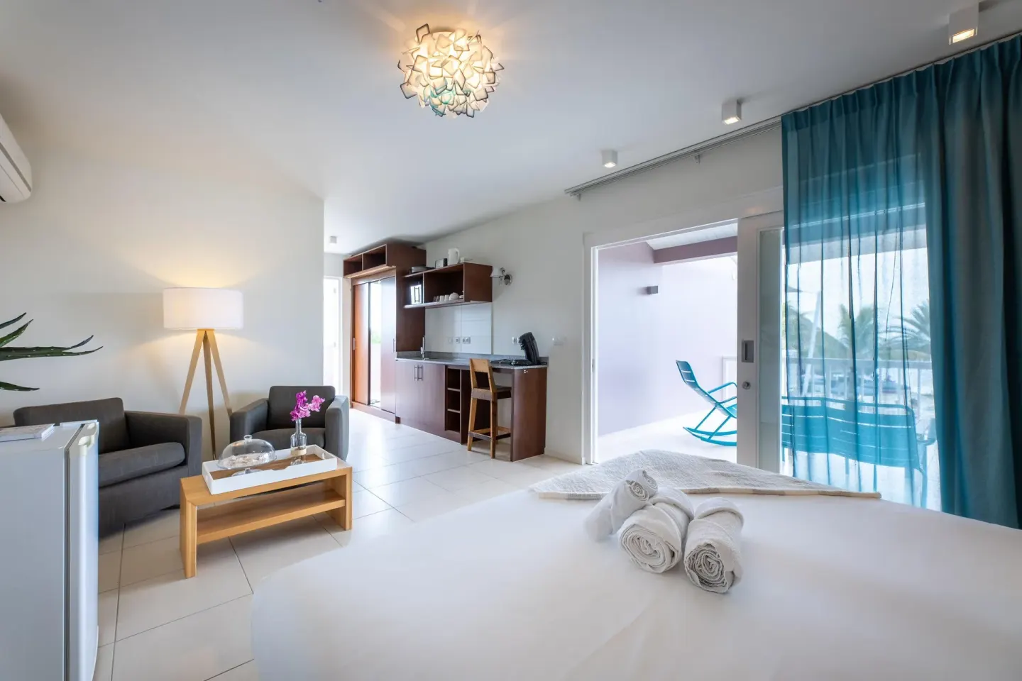 Deluxe Room Garden View bed, kitchenette, and terrace at Coral Estate Luxury Resort.
