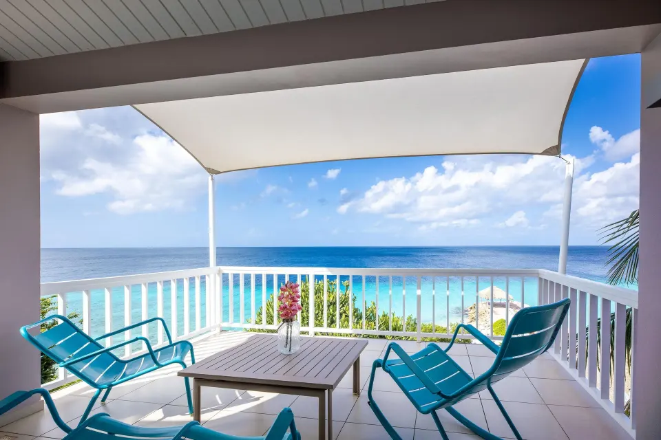 Deluxe Room Ocean View balcony with turquoise chairs at Coral Estate Luxury Resort.