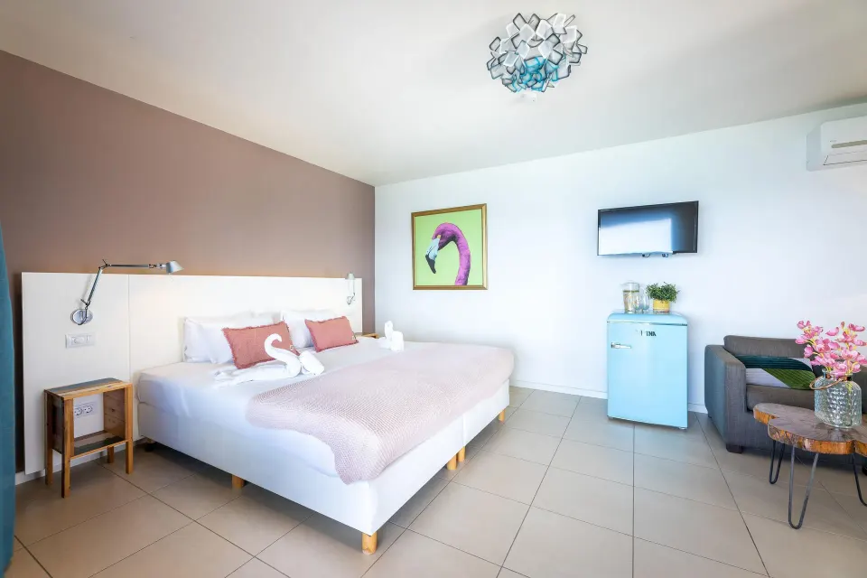 Deluxe Room Ocean View king bed with sofa and wall art at Coral Estate Luxury Resort.