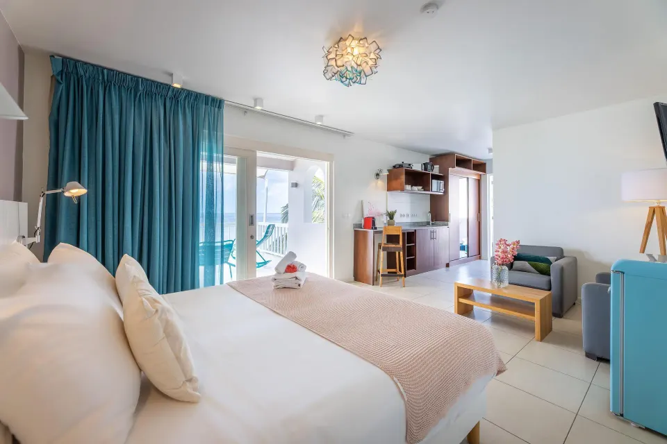 Deluxe Room king bed, kitchenette, sitting area, and balcony at Coral Estate Luxury Resort.
