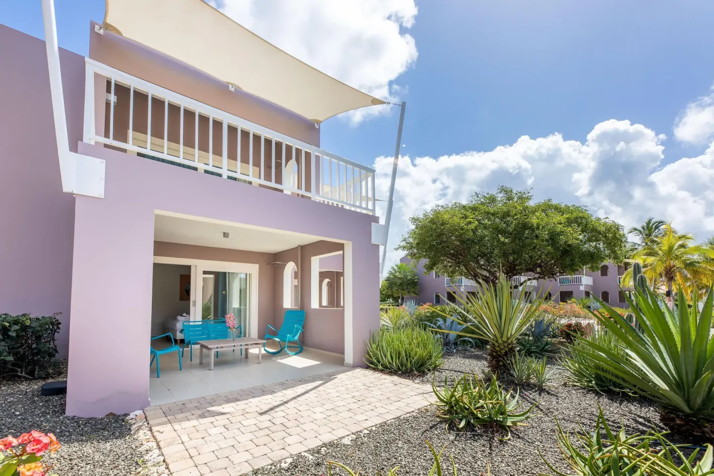 Deluxe Room patio with turquoise chairs and garden at Coral Estate Luxury Resort.
