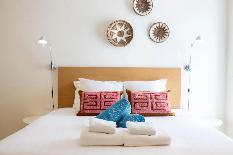 Superior Apartment bed with pink pillows and woven wall decor at Coral Estate Luxury Resort.