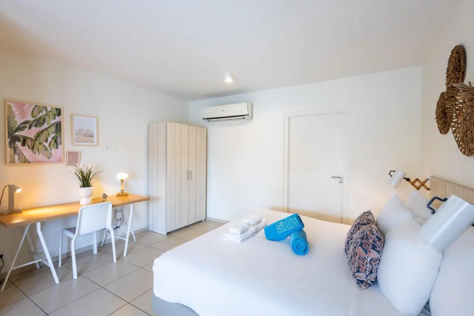 Superior apartment bedroom with white bed and desk at Coral Estate Luxury Resort.