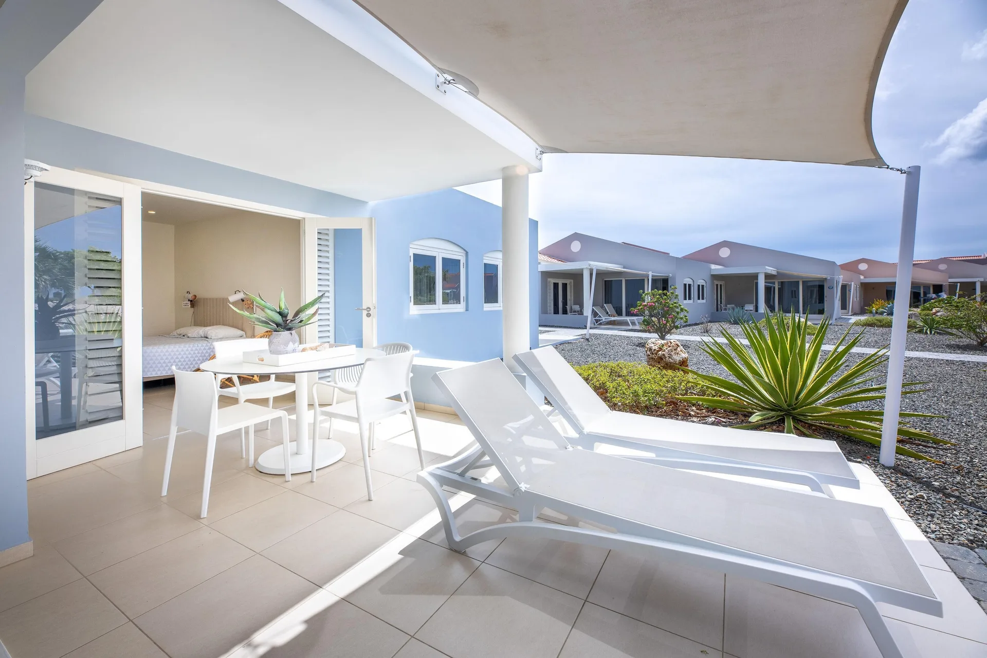 Garden-view apartment terrace with loungers and bedroom at Coral Estate Luxury Resort.