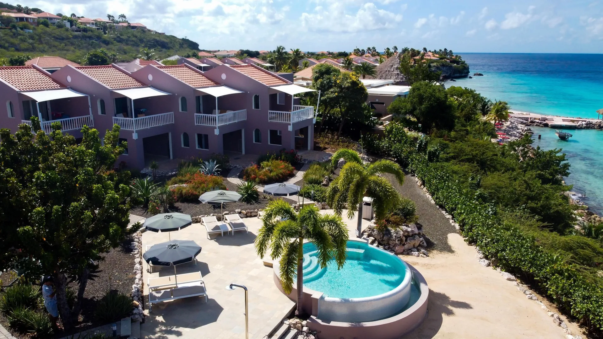 Oceanfront rooms, pool terrace, and shoreline at Coral Estate Luxury Resort.