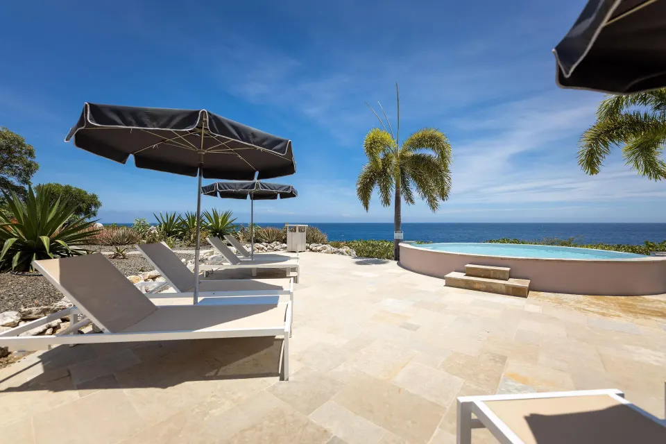 VIP area terrace with sunbeds, umbrellas, pool, and ocean at Coral Estate Luxury Resort.