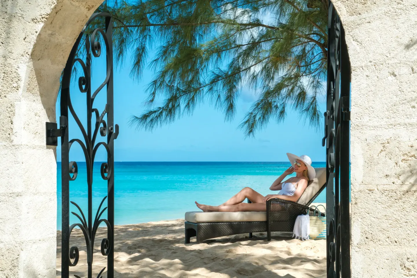 A shaded beach lounger is framed by an arched gate at Coral Reef Club.